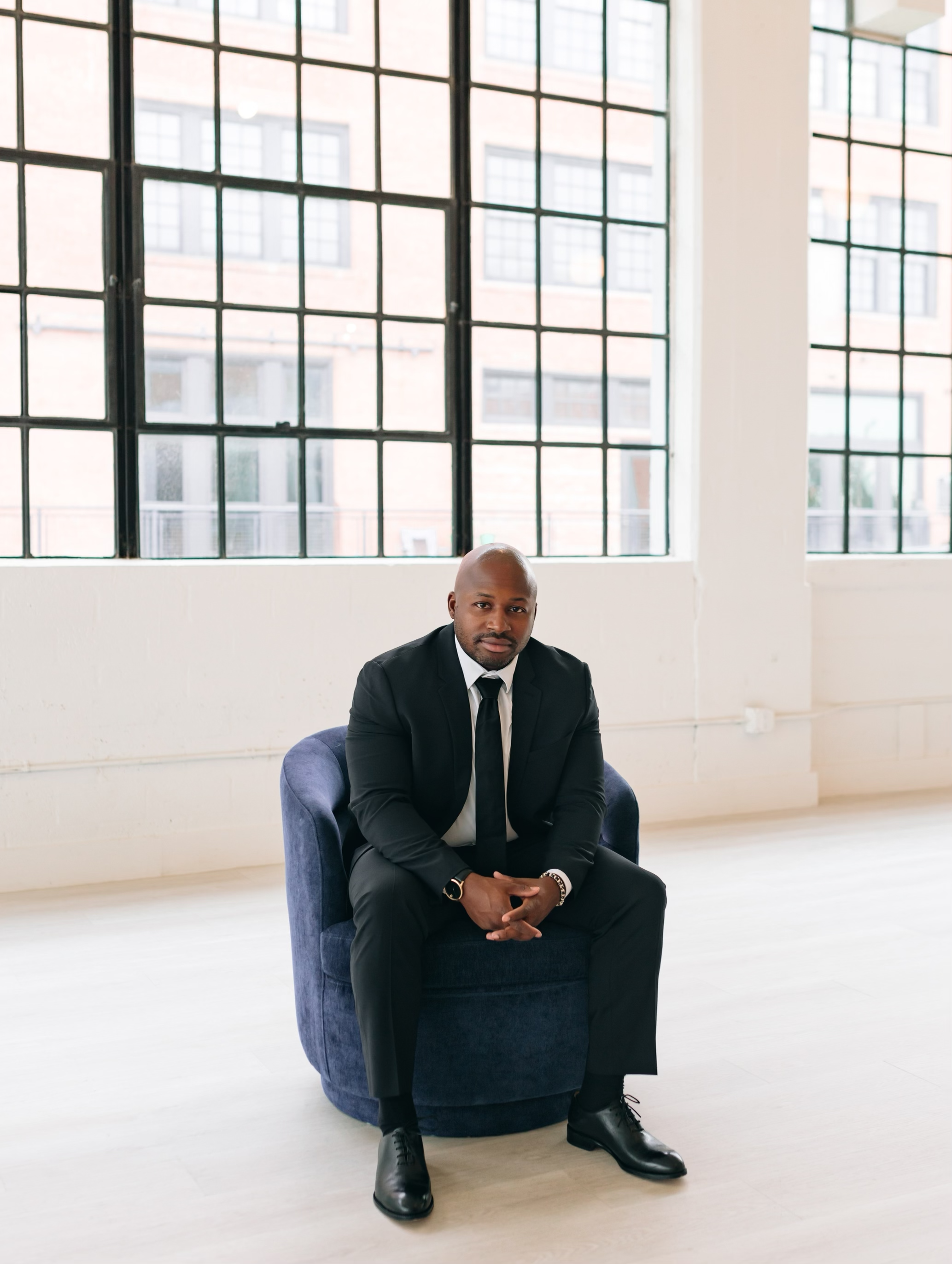 Jevon sitting in chair in black suit